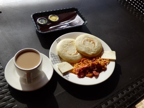 a plate of food with pancakes and cheese and a cup of coffee at Hostal Alto de la Montaña in Minca