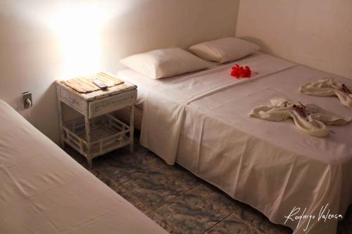a bedroom with two beds and a table with towels on them at Pousada Dois Irmãos in Fernando de Noronha