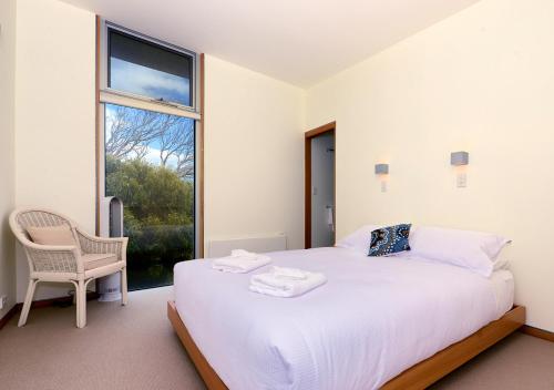 a white bedroom with a large bed and a window at Cloudy Bay Beach House in South Bruny