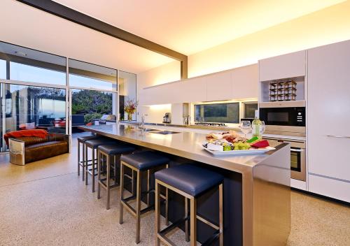 a kitchen with a large island with bar stools at Cloudy Bay Beach House in South Bruny