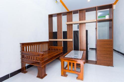Habitación con banco de madera y mesa. en SUPER OYO 2873 Griya Annisa, en Tegal