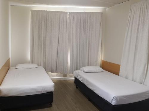 
a hotel room with two beds and two nightstands at Dandenong Motel in Dandenong
