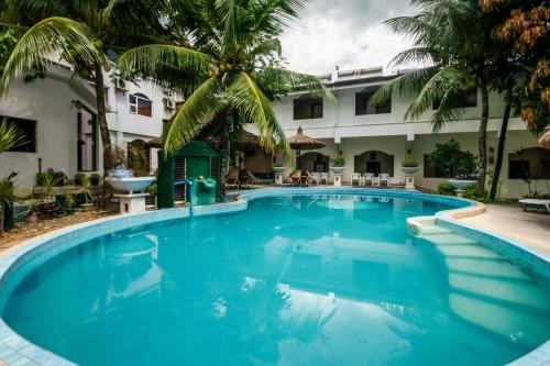 uma piscina em frente a um hotel com palmeiras em Cebu Hilltop Hotel em Cebu