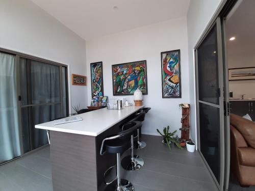 a kitchen with a white counter and black stools at Spring Beach Garden Retreat in Spring Beach