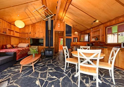 ein Wohnzimmer mit einem Bett, einem Tisch und Stühlen in der Unterkunft Saintys Creek Cottage in South Bruny