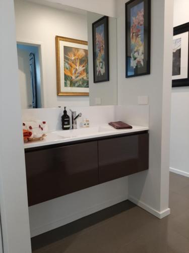 a bathroom with a sink and paintings on the wall at Spring Beach Garden Retreat in Spring Beach