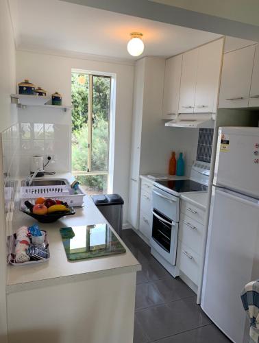 a kitchen with white cabinets and a white refrigerator at Relax On Bingham in Goolwa