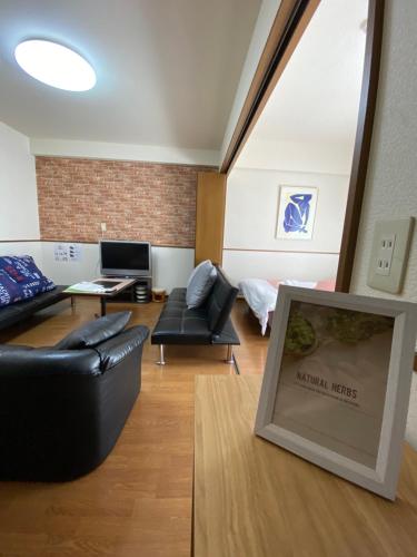 a living room with a black leather couch and a table at Laforet Tokaichi in Hiroshima