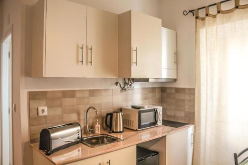 a kitchen with white cabinets and a sink and a microwave at Elvas GuestHouse in Elvas