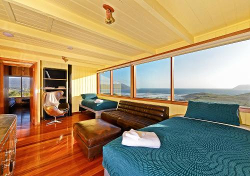 a bedroom with a bed and a couch and windows at Cloudy Bay Villa in South Bruny
