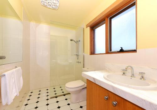 een badkamer met een wastafel, een toilet en een raam bij Cloudy Bay Villa in South Bruny