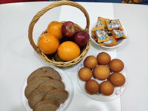 a table with fruits and bread and a basket of fruit at Lux Apartment Karakol Center in Karakol
