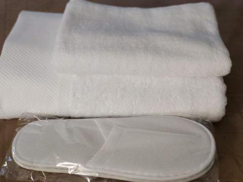a stack of white towels and a plastic container at Lux Apartment Karakol Center in Karakol