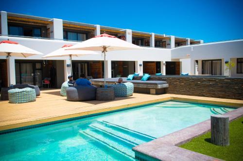 a villa with a swimming pool and a house at Windtown Lagoon Hotel in Langebaan