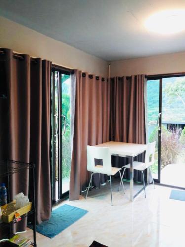 a dining room with a table and chairs and windows at Thanorm Rak Resort in Khao Kho