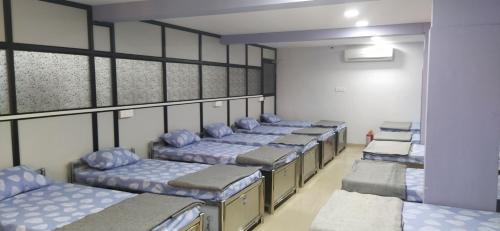 een rij bedden in een kamer met blauwe kussens bij Shiv Sai Dormitory in Vadodara