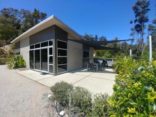 a house with glass doors and a patio at Ryder Ridge Holiday Home in Motueka