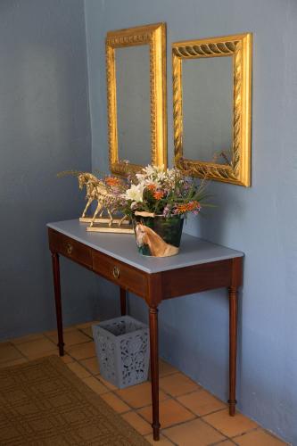 a table with two mirrors and a vase with flowers on it at Bridgewaters Horse Park Tranquil Country Cottage in Hekpoort