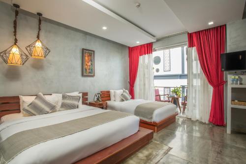 two beds in a bedroom with red curtains at Cambana Residence in Siem Reap