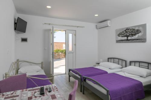 duas camas num quarto com lençóis roxos em Apartments Karol & Mara em Mlini