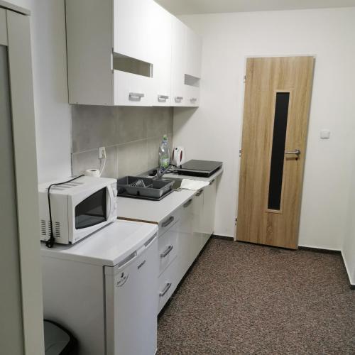 a white kitchen with a microwave and a sink at Penzion Stella in Prostějov
