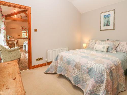 a bedroom with a bed and a chair in it at Maltkiln Cottage At Crook Hall Farm in Mawdesley