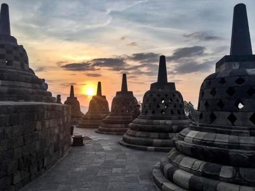 a view of a group of stone temples at sunset at Manohara Resort in Borobudur