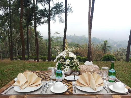 a table with plates and bottles and flowers on it at Manohara Resort in Borobudur
