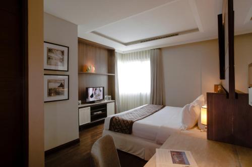 a hotel room with a bed and a window at Ascott Waterplace Surabaya in Surabaya