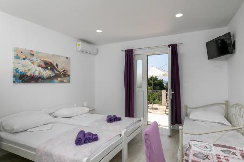 um quarto branco com 2 camas e uma janela em Apartments Karol & Mara em Mlini