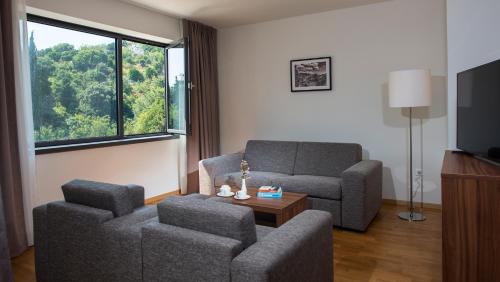 a living room with two chairs and a couch and a tv at Maistra Select Srebreno Premium Apartments in Mlini