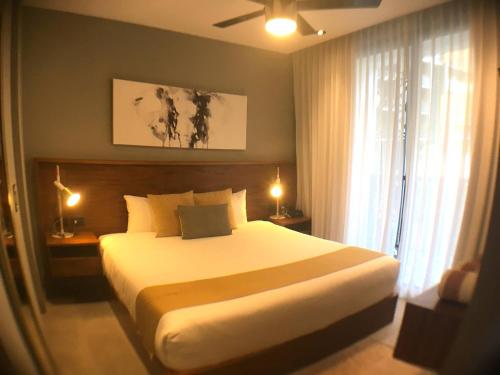 Un dormitorio con una gran cama blanca y una ventana en It Residence Top Location Luxury 2 Br Two Roof Pools Beach Club included, en Playa del Carmen