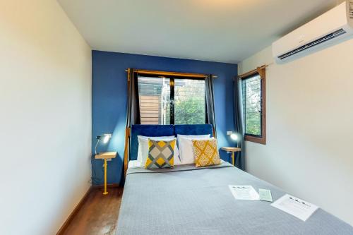 a bedroom with blue walls and a bed with pillows at Inn The Trees Cabañas in Placencia