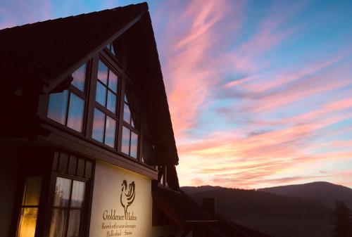 a building with a sunset in the sky at Goldener Hahn B&B Baiersbronn - Ferienwohnungen mit Hygge Pool & Sauna in Baiersbronn
