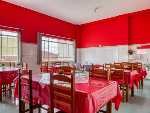 un restaurant avec des murs rouges, des tables et des chaises en bois dans l'établissement Palace Hotel Itapira, à Itapira