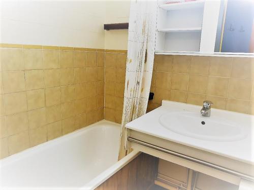 a bathroom with a sink and a bath tub at Résidence Chanteneige - Freeloc Immobilier in Les Menuires