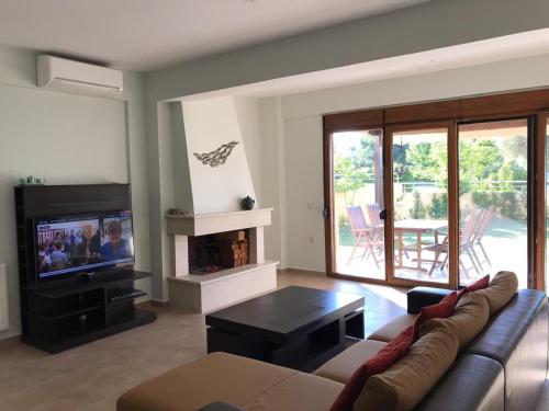 a living room with a couch and a tv at Villa Dimitrios in Kriopigi