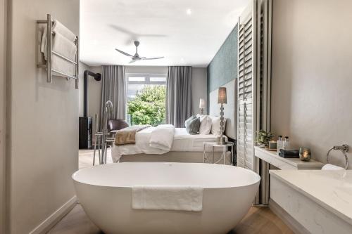 a bathroom with a bath tub and a bedroom at Franschhoek Boutique Hotel - Lion Roars Hotels & Lodges in Franschhoek
