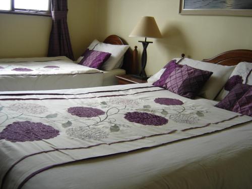 Springlawn في Clarinbridge: غرفة نوم بسريرين ذات أغطية أرجوانية وبيضاء