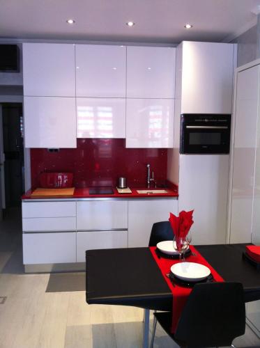 une cuisine avec des placards blancs et une table rouge dans l'établissement MONACO DREAM, à Beausoleil