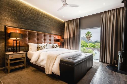 a bedroom with a large bed and a large window at Franschhoek Boutique Hotel - Lion Roars Hotels & Lodges in Franschhoek
