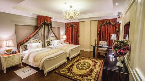 a bedroom with two beds and a chandelier at The Orchard Resort & Spa Melaka I World Spa Awards Winner I Free Access to Outdoor Spa Pool in Malacca