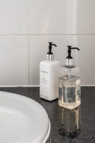 two soap dispensers sitting next to a toilet in a bathroom at At the Beach - Muizenberg in Cape Town