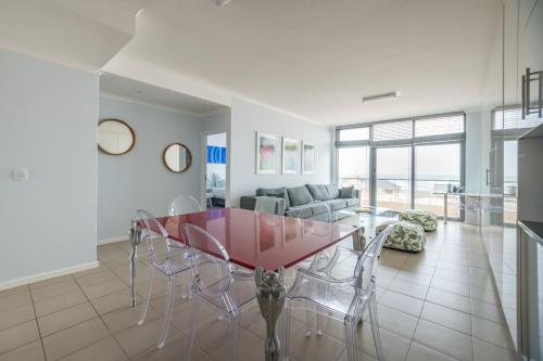 een eetkamer met een rode tafel en stoelen bij At the Beach - Muizenberg in Kaapstad