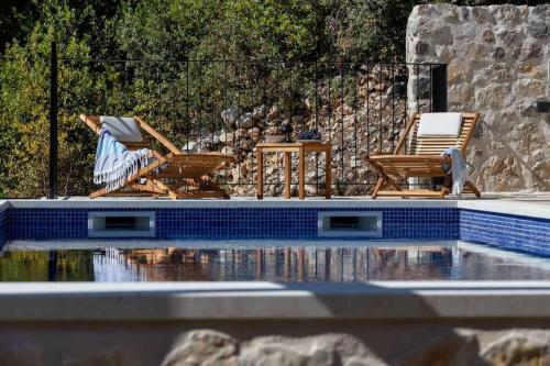 Duas cadeiras estão sentadas ao lado de uma piscina em Holiday home Marijana em Zaostrog