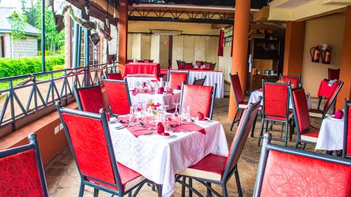 une salle à manger avec des tables, des chaises et des chaises rouges dans l'établissement Anka Resort, à Naro Moru