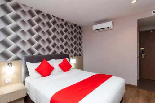 a bedroom with a large white bed with red pillows at Hotel 101 Ulu Tiram in Ulu Tiram