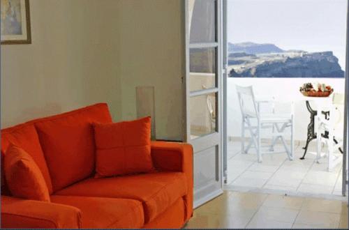 an orange couch in a living room with an open door at Tzekos Villas in Fira