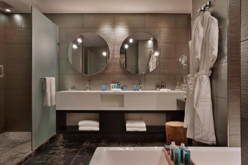 a bathroom with a tub and a sink and mirrors at Royal Beach Hotel Tel Aviv by Isrotel Exclusive in Tel Aviv
