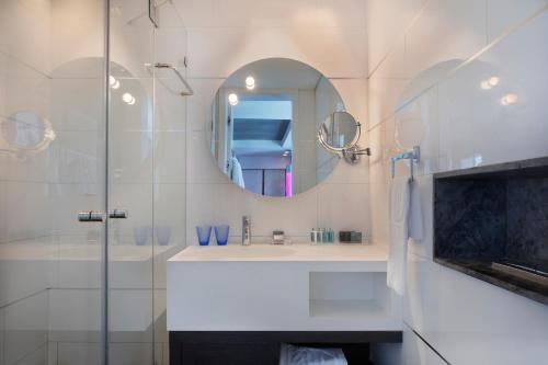 a white bathroom with a sink and a mirror at Royal Beach Hotel Tel Aviv by Isrotel Exclusive in Tel Aviv